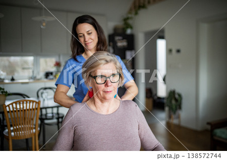 Physiotherapist helping senior woman with neck exercise, home therapy session. 138572744
