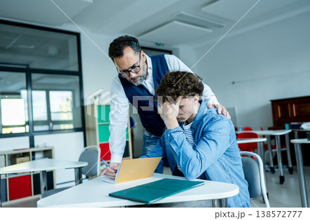 Teacher supporting struggling student with learning difficulties during lesson. Teacher supporting struggling student with learning difficulties during lesson. 138572777