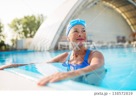 Elderly woman in swimming pool. Older female exercising for vitality and longevity. 138572819