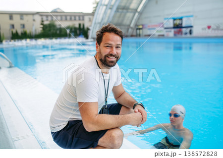 Coach giving advice to young swimme in water, standing by pool. 138572828