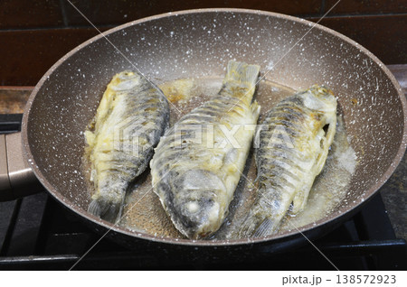 cooking freshwater fish crucian carp in a frying pan cooking freshwater fish crucian carp in a frying pan 138572923