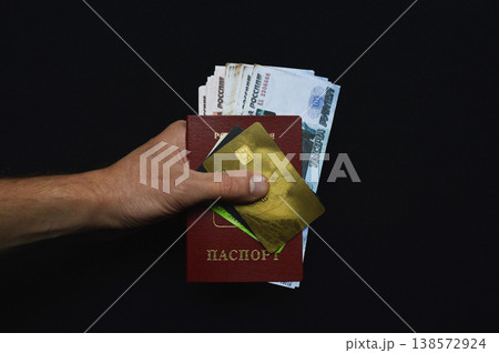 A Russian citizen's passport, rubles, and bank cards in a man's hand 138572924