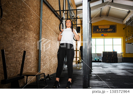 Woman preparing for workout on gymnastics rings in gym Woman preparing for workout on gymnastics rings in gym 138572964