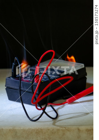 Smoking multimeter with wires after fire short circuit and overload 138573274
