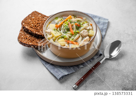 Chicken noodle soup with fresh dill in a bowl on a light textured background 138573331