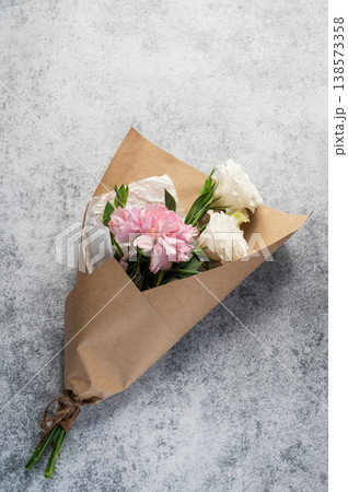A delicate bouquet of flowers with pink carnations and white eustoma on a light, textured background 138573358