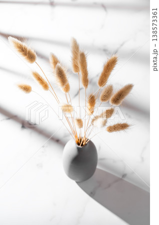 Minimalistic bouquet of dried herbs in a ceramic vase on a marble background. Minimalistic bouquet of dried herbs in a ceramic vase on a marble background. 138573361