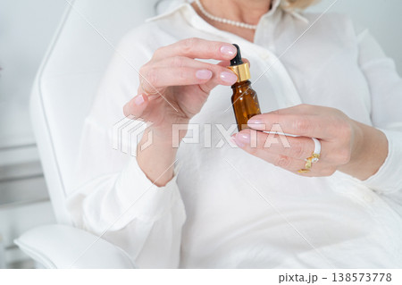 A woman is gracefully holding an essential oil bottle with a dropper in a beautifully elegant, serene setting 138573778