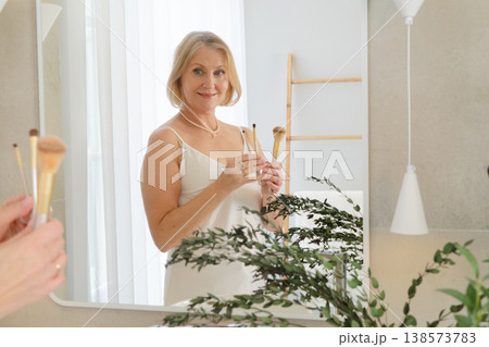 A Radiant Woman Happily Engaging in Her Skincare Ritual in a Bright, Cheerful Bathroom Decorated with Plants A Radiant Woman Happily Engaging in Her Skincare Ritual in a Bright, Cheerful Bathroom Decorated with Plants 138573783