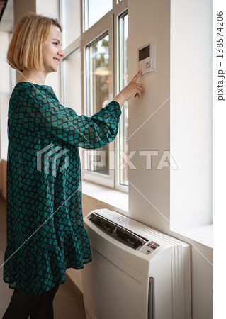 Woman in Green Dress Standing Next to Window Woman in Green Dress Standing Next to Window 138574206