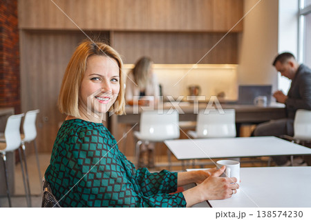 Woman Sitting at Table With Cup of Coffee Woman Sitting at Table With Cup of Coffee 138574230