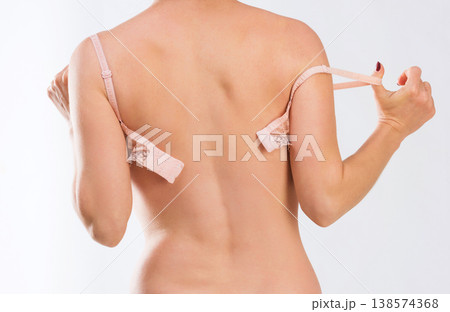 Figure of woman in peachy lingerie taking off her bra, standing in her underpants, backshot Figure of woman in peachy lingerie taking off her bra, standing in her underpants, backshot 138574368