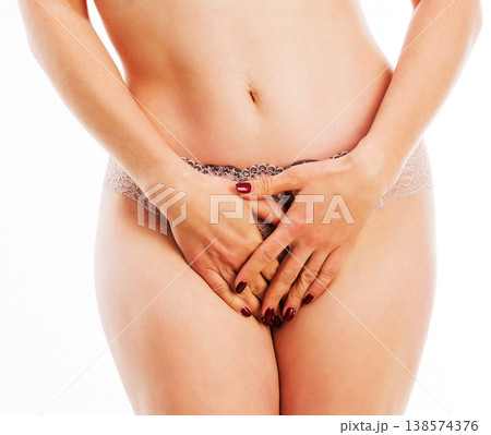 Attractive woman in pastel underwear standing and covering her abdomen, isolated on a white background 138574376