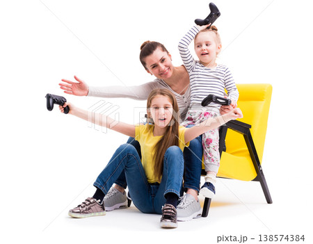 Mother and two daughters playing games with joystick, winning and being happy and cheerful Mother and two daughters playing games with joystick, winning and being happy and cheerful 138574384