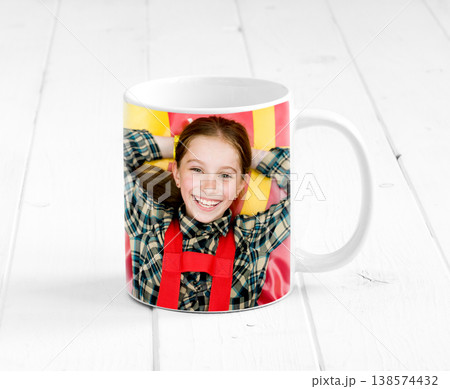 Big colorful cup on the planked wooden surface with a child printed on it Big colorful cup on the planked wooden surface with a child printed on it 138574432