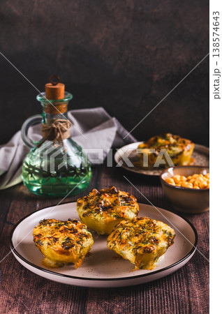 Potato halves baked with cheese, garlic and herbs on a plate on the table vertical view Potato halves baked with cheese, garlic and herbs on a plate on the table vertical view 138574643