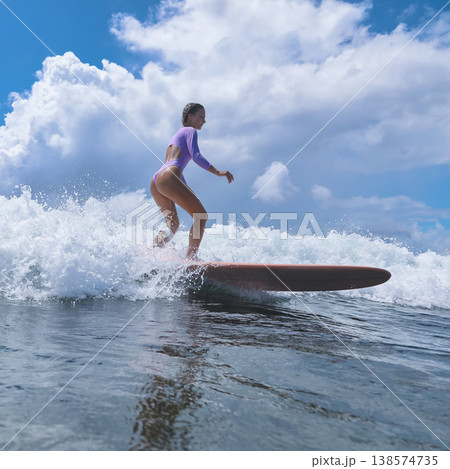 Teen Woman Practicing Stance On Surfboard Amid Gentle Ocean Colors And Clouds 138574735