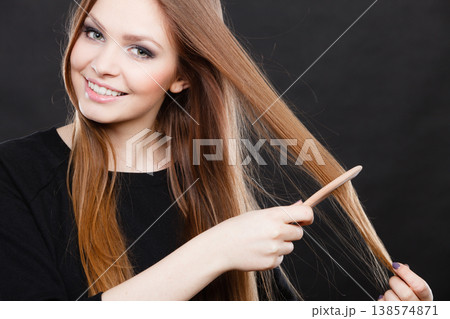 Long haired woman combing her hair. 138574871