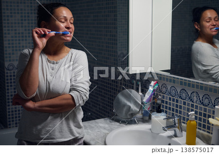 Middle-Aged Woman Brushing Teeth in Bathroom During Morning Skincare and Personal Care Routine Middle-Aged Woman Brushing Teeth in Bathroom During Morning Skincare and Personal Care Routine 138575017