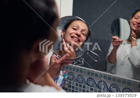 Middle-Aged Woman in Pyjamas Doing Morning Skincare and Self-Care Routine in Bathroom Mirror Middle-Aged Woman in Pyjamas Doing Morning Skincare and Self-Care Routine in Bathroom Mirror 138575029