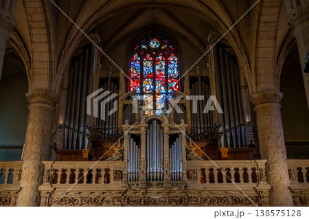 an organ in a Catholic church against the backdrop of a stained glass window 138575128