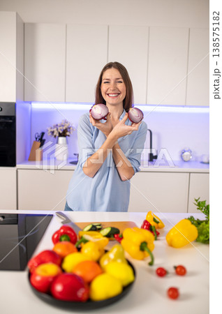 Pretty young caucasian woman holding slices of onion in hands while cooking in the kitchen Pretty young caucasian woman holding slices of onion in hands while cooking in the kitchen 138575182