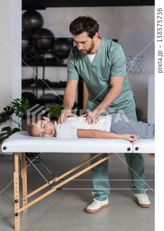 Specialist massaging child back during recovery session Specialist massaging child back during recovery session 138575736