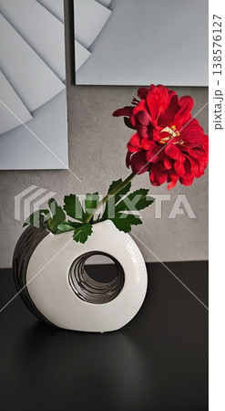 Bright red flower in modern designer vase on grey background Bright red flower in modern designer vase on grey background 138576127