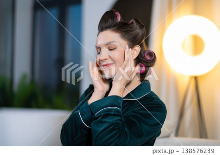 Young pretty woman using peel off mask for her face and looking contented Young pretty woman using peel off mask for her face and looking contented 138576239