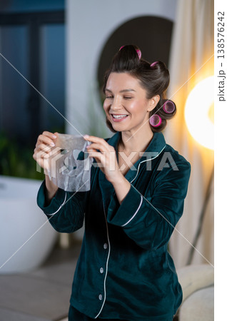 Young pretty woman using peel off mask for her face and looking contented Young pretty woman using peel off mask for her face and looking contented 138576242