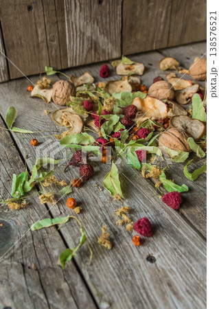 Dried delicious delicacies. Dry pieces of linden, rose hips, pears, raspberries, apples and walnuts snack on a wooden background Dried delicious delicacies. Dry pieces of linden, rose hips, pears, raspberries, apples and walnuts snack on a wooden background 138576521