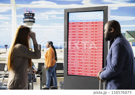 Helpless travelers in disbelief after cancellation of all flights in airport lounge, bad news of suspended travel and no departures. Passengers with anxiety looking at information screen Helpless travelers in disbelief after cancellation of all flights in airport lounge, bad news of suspended travel and no departures. Passengers with anxiety looking at information screen 138576875