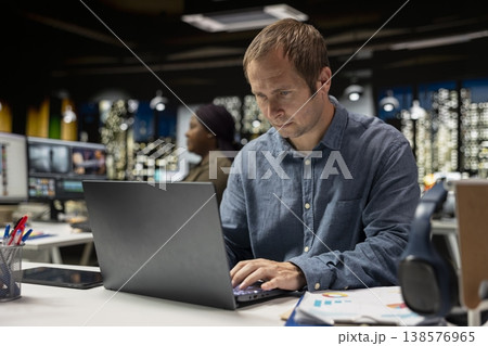 Focused businessman using computer to analyze insights and performance metrics, making projections and data visualization. Employee share reports to improve corporate development. 138576965
