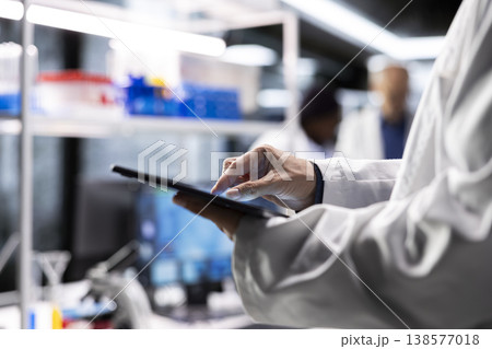 Close up of lab expert at work reviews chemical data on tablet, medical discovery in a laboratory. Using modern equipment for bioscience and molecular research to drive pharmaceutical progress. Close up of lab expert at work reviews chemical data on tablet, medical discovery in a laboratory. Using modern equipment for bioscience and molecular research to drive pharmaceutical progress. 138577018
