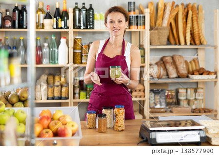 Adult woman seller offering green peas in grocery 138577990