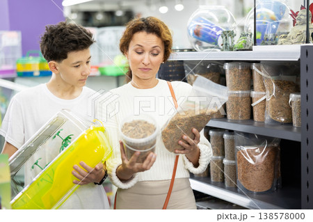 Family mom and son in animal goods store examines packaging of dry food for turtles Family mom and son in animal goods store examines packaging of dry food for turtles 138578000