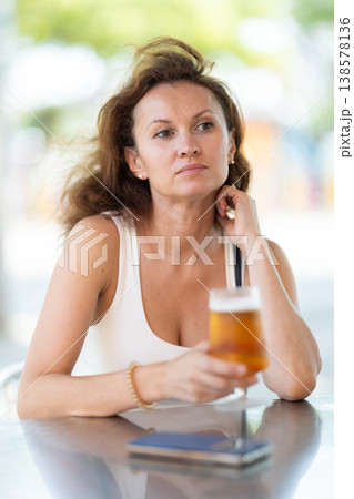 Adult woman drinking beer on cafe terrace Adult woman drinking beer on cafe terrace 138578136