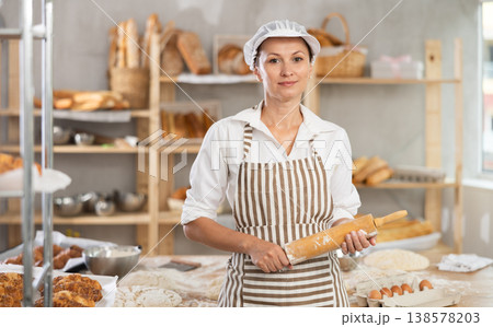 Female baker with rolling pin standing in bakery Female baker with rolling pin standing in bakery 138578203
