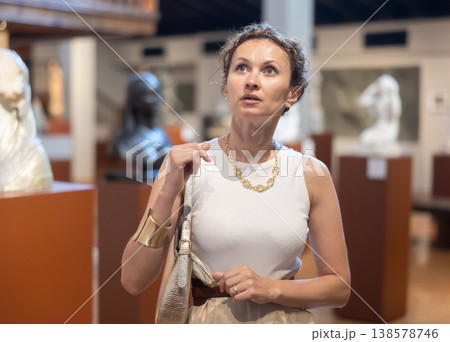 Woman visit museum, examines masterpiece at exhibition Woman visit museum, examines masterpiece at exhibition 138578746