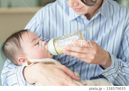赤ちゃんにミルクを与えるお父さん 赤ちゃんにミルクを与えるお父さん 138579035