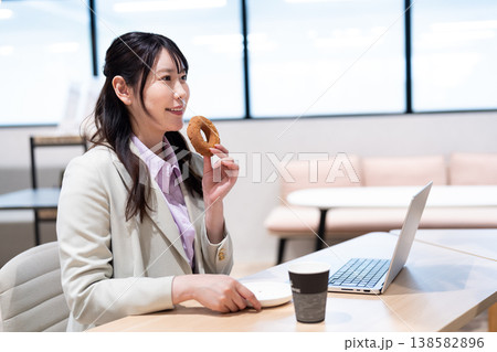 仕事の合間にコーヒーとドーナツでリラックスする女性 138582896