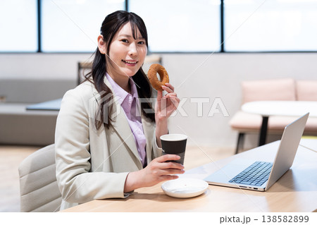 仕事の合間にコーヒーとドーナツでリラックスする女性 138582899