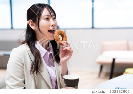 仕事の合間にコーヒーとドーナツでリラックスする女性 138582905