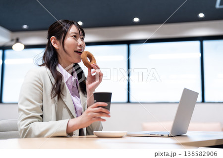 仕事の合間にコーヒーとドーナツでリラックスする女性 138582906