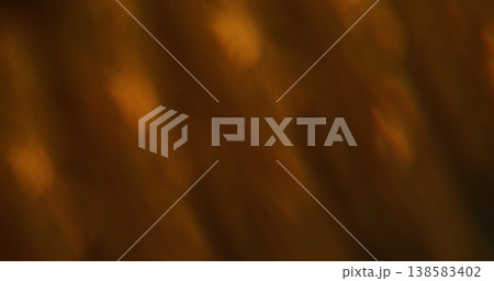 Defocused beam lens. Optical leak. Orange brown light shimmer on dark background. Crystal prism rays luminosity abstract color texture. 138583402