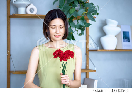 赤いカーネーションを手に持ち微笑む日本人女性 母の日のイメージ 138583500