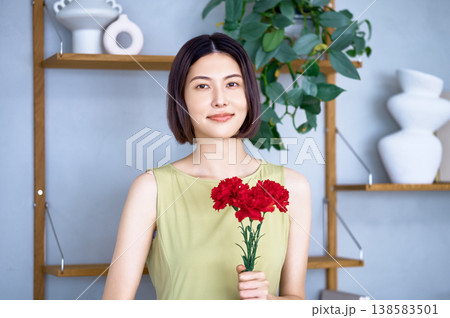 母の日のプレゼントに赤いカーネーションを持って微笑む若い日本人女性 138583501