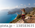 Young woman looking at Oludeniz beach, blue lagoon with clear bright turquoise water, Lycia coast. Summer day walk by Lycian way at family vacation in Mediterranean Sea, Fethye, Antalya region, Turkey 138583635