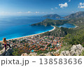 Young woman looking at Oludeniz beach, blue lagoon with clear bright turquoise water, Lycia coast. Summer day walk by Lycian way at family vacation in Mediterranean Sea, Fethye, Antalya region, Turkey 138583636