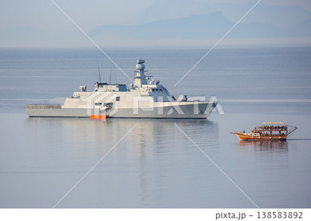 Naval ship and boat on calm water near coastline during daylight hours in tropical region 138583892